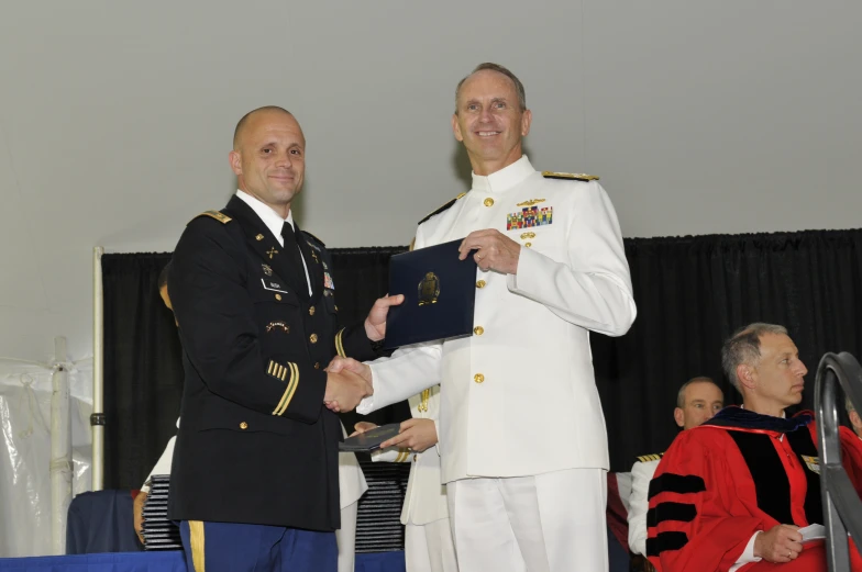 two military officers and men in uniforms at a ceremony