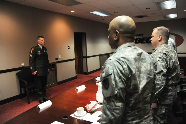 two military men stand in an office talking