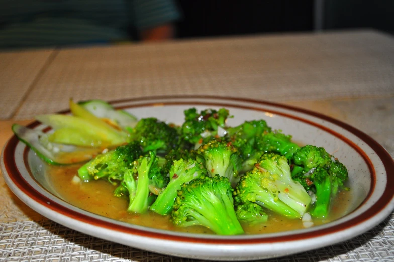 a plate with broccoli and a brown colored liquid