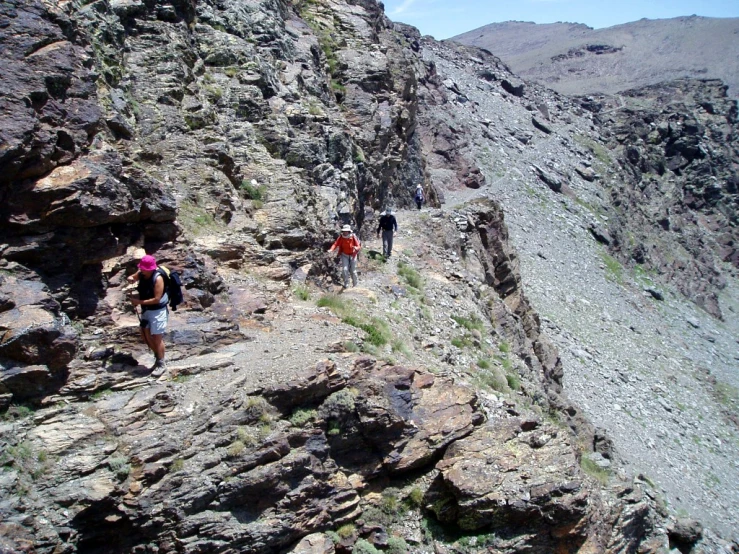 some people are walking up a steep rock mountain