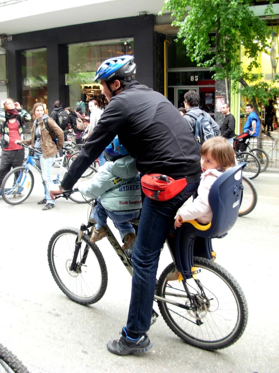 a man on a bicycle rides alongside a child in a seat
