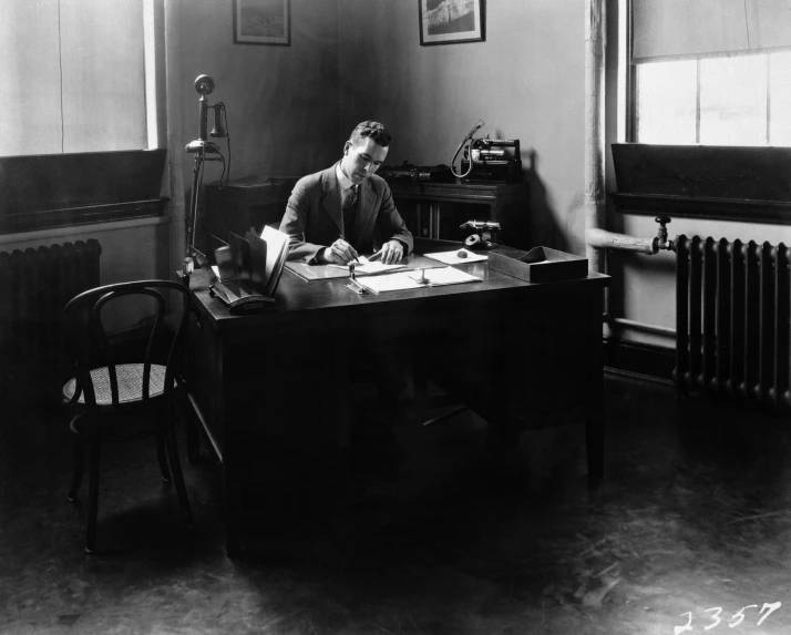 a woman sitting at a desk writing on a piece of paper