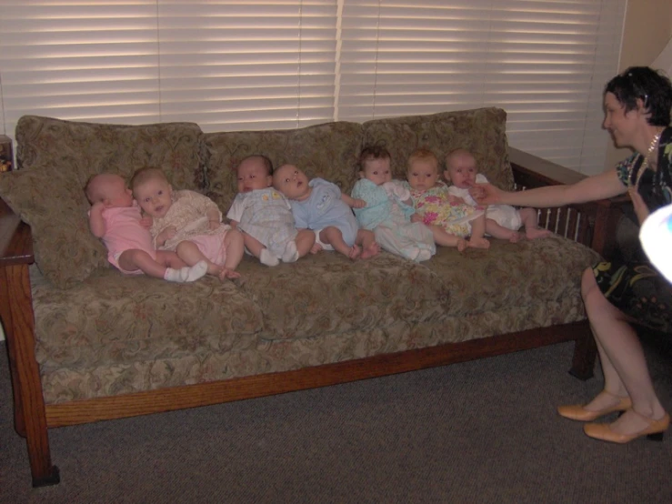 woman sitting on couch playing with babies in room