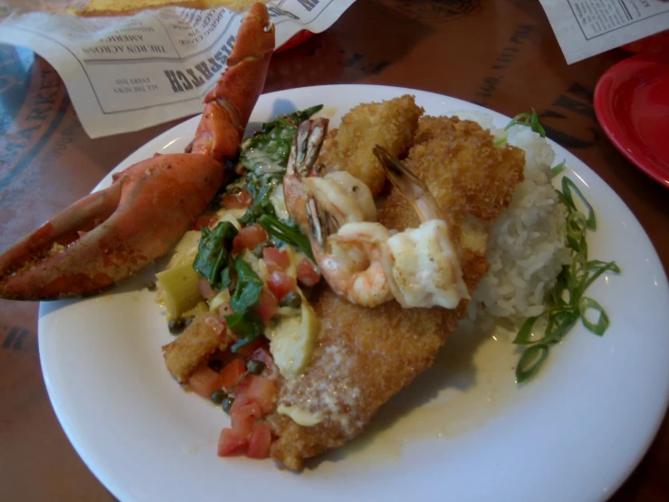 the plate contains several different food items such as bread and a lobster