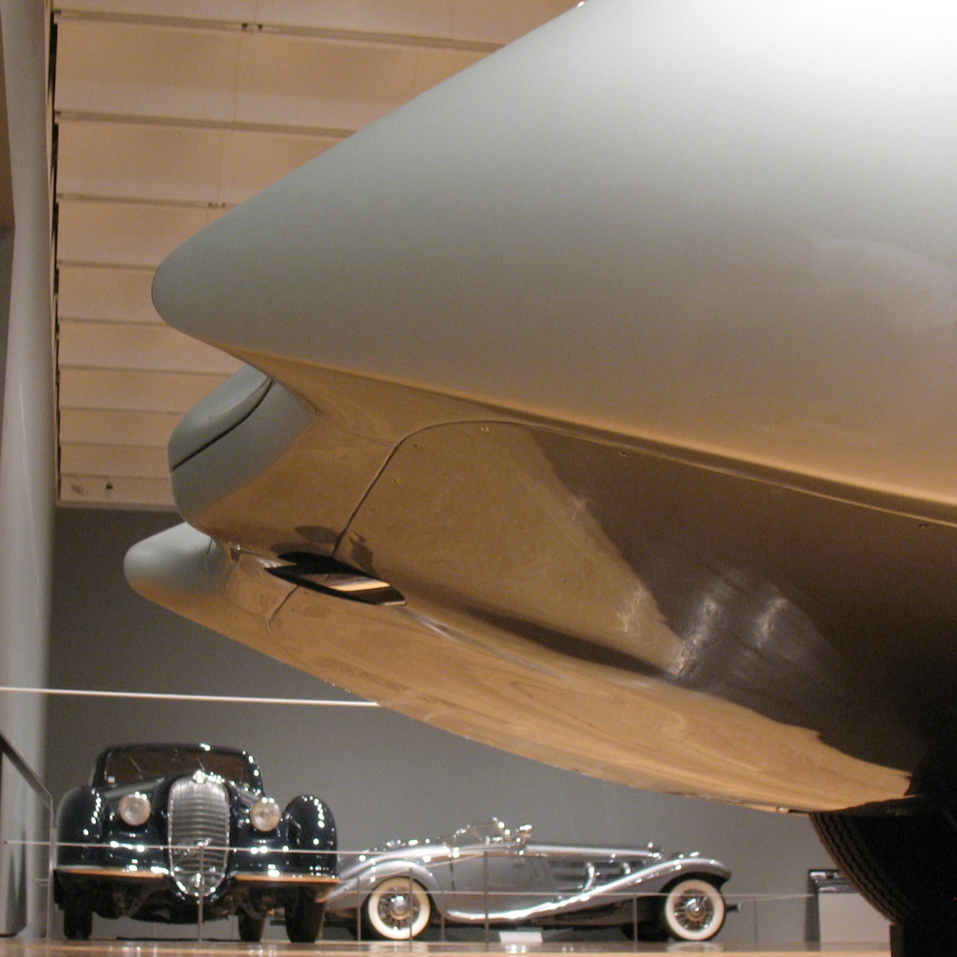 two cars on display in a building and a propeller