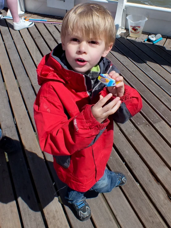 a child holds a candy bar while standing on a deck