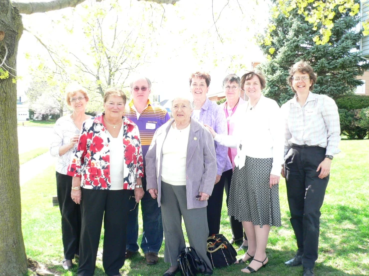 an older group poses under the tree with suitcases