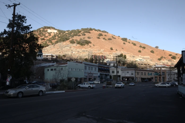 the cars are parked in the streets with a hill in the background