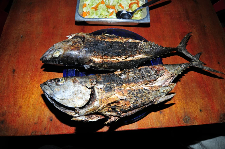 two fish that are laying on top of a wooden table