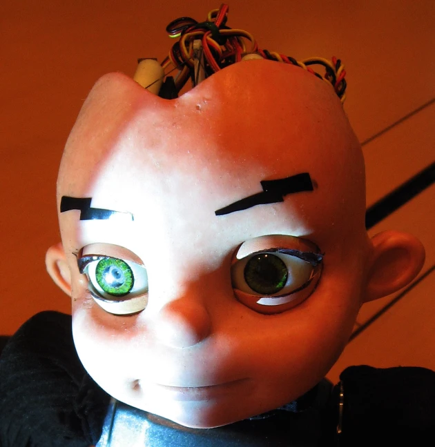 there is an orange doll with green eyes and hair on its head