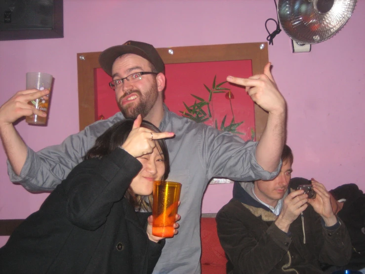 a man holding up a glass of liquid while two people pose for the camera