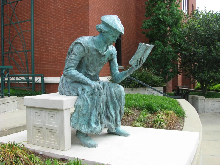 there is a bronze statue of a woman reading a book