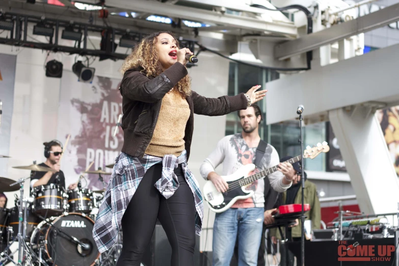 a woman in black pants and a yellow jacket on stage