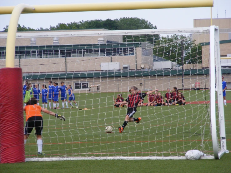 soccer players on the field in front of a goalie net