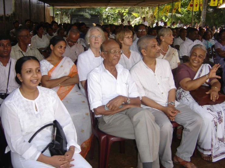 many people in white shirts sitting in chairs