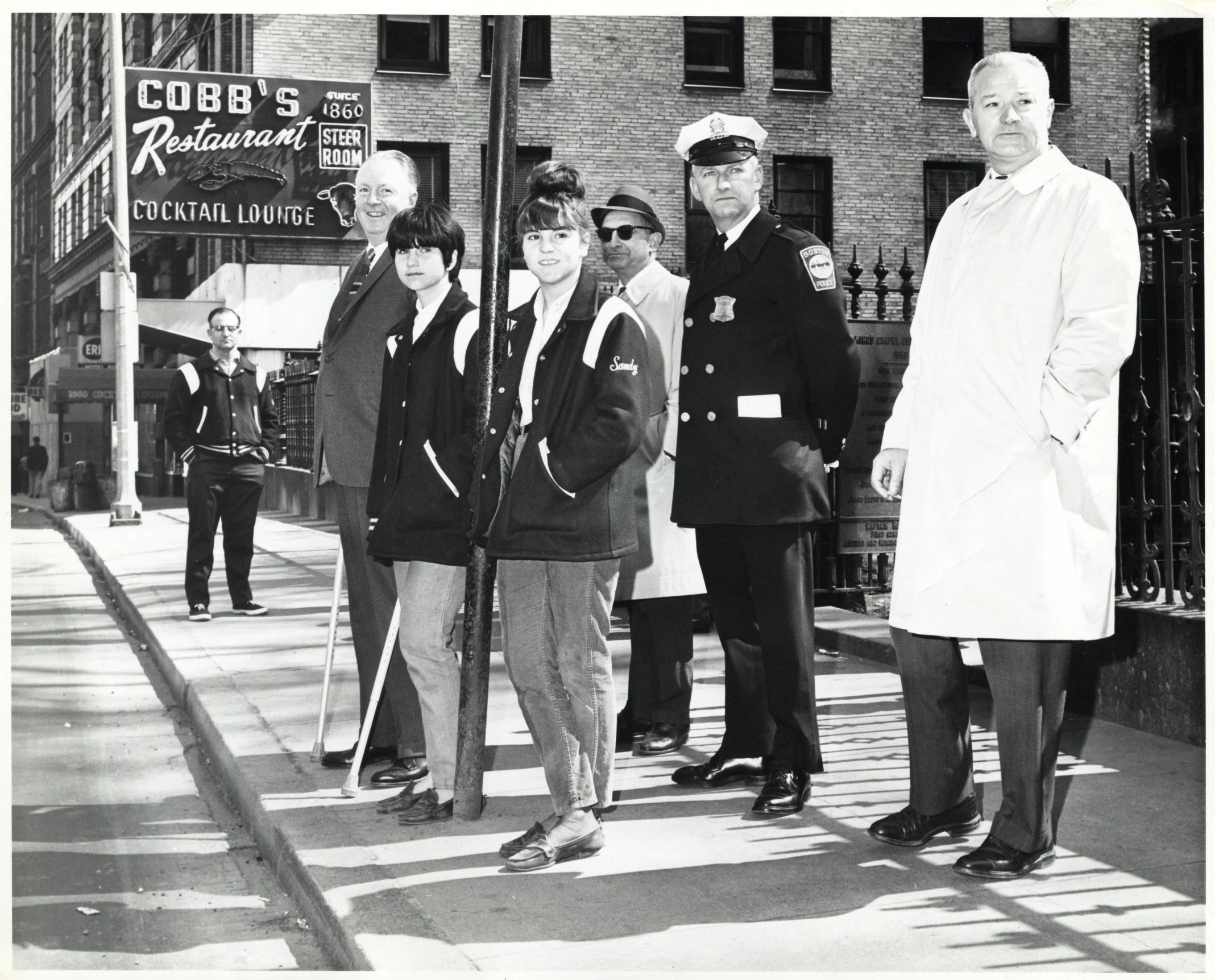 a group of men stand by a sign post in a street