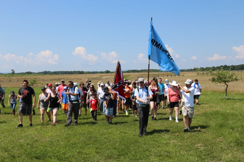 a crowd of people are on the grass watching a man with a flag