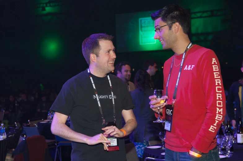 two men are standing at a convention event and talking to each other