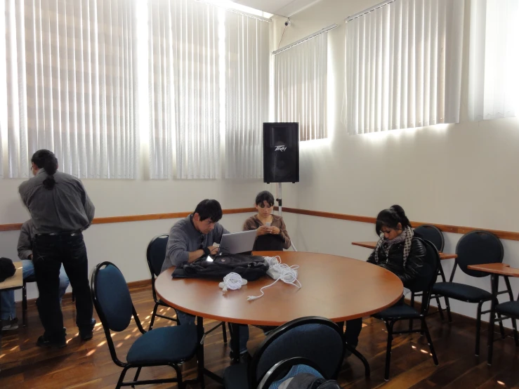 people sitting at tables in a room using laptop computers