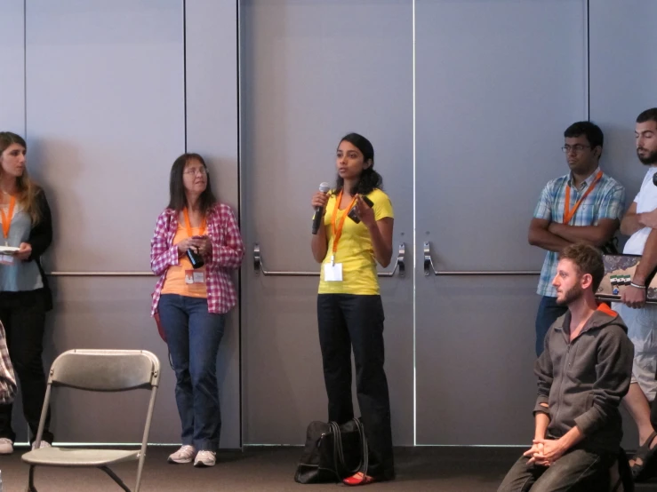 three people standing at the front of a room with microphones