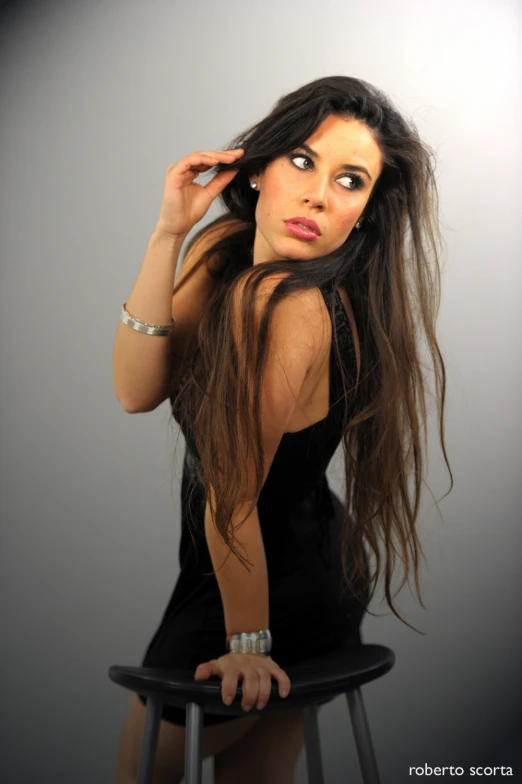 a woman sitting on top of a stool with her hair in the air