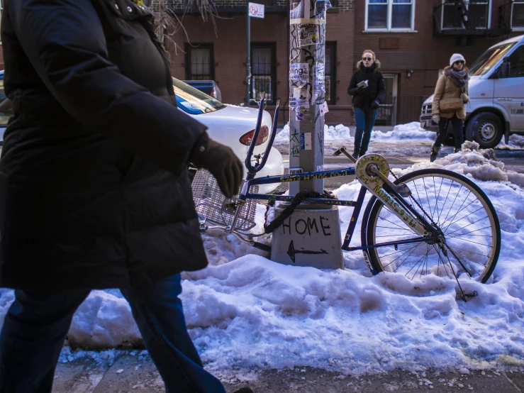 a bike  to a pole on the side of a snowy street