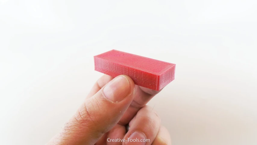 a persons hand holding a bright pink piece of sponge