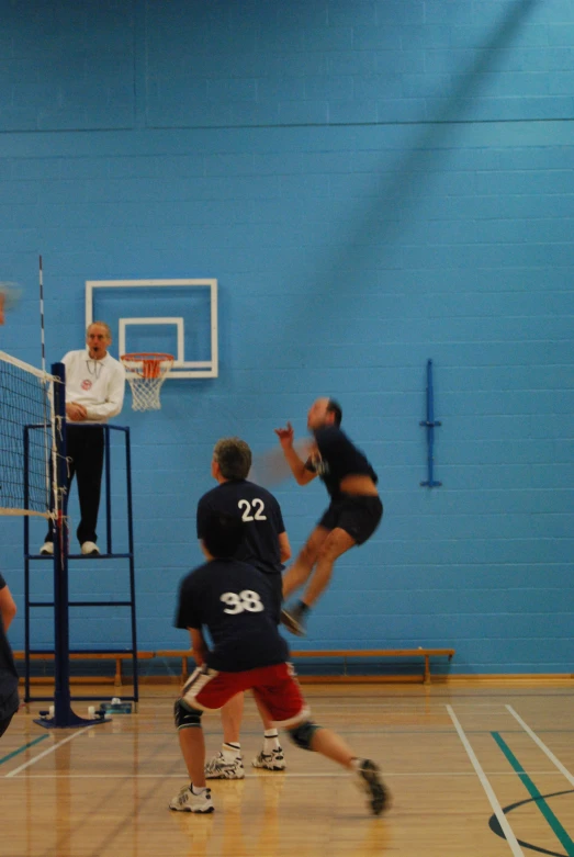 men playing basketball on a gym court with a referee watching