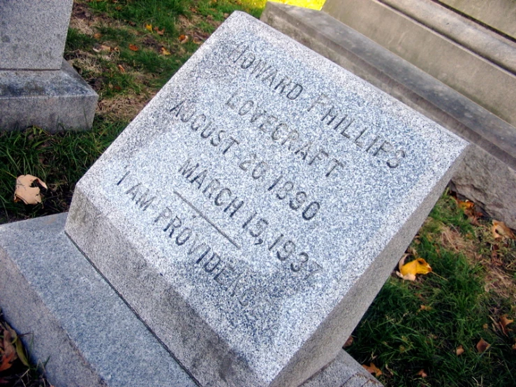 a small tombstone sitting in the grass with writing on it