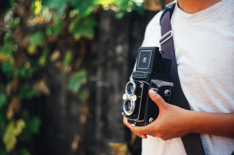 a man standing next to trees holding a camera