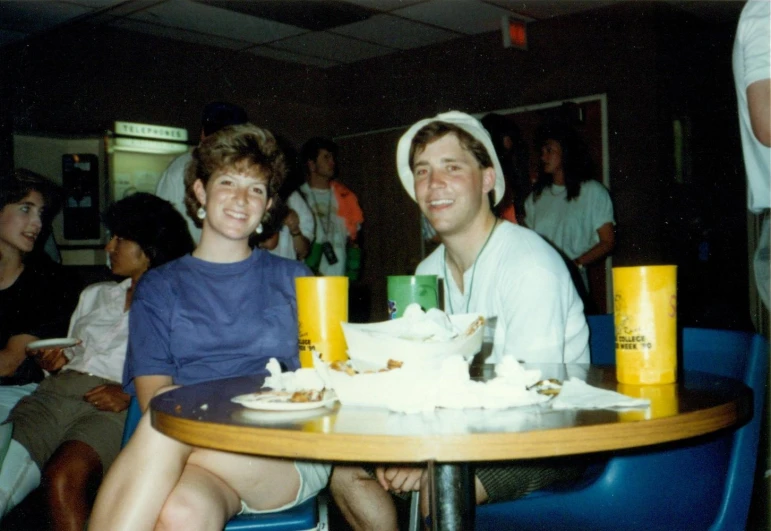 a man sitting at a table next to a woman and another person