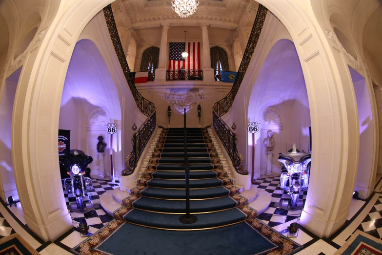 a hall of stairs with blue carpet and lights