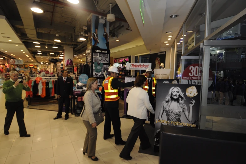 many people standing around in a store with a sign in front of them