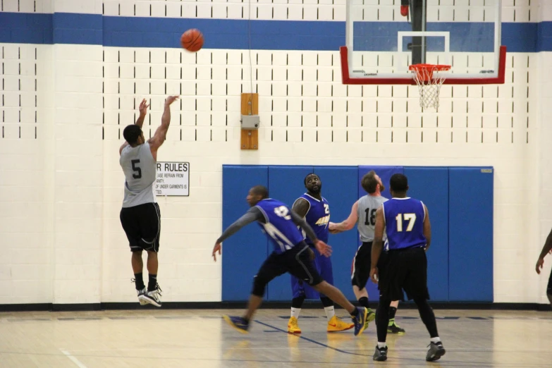 a group of guys play a game of basketball