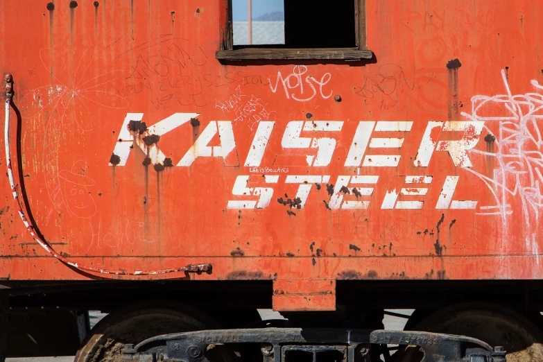 an orange train car with graffiti is seen on the outside