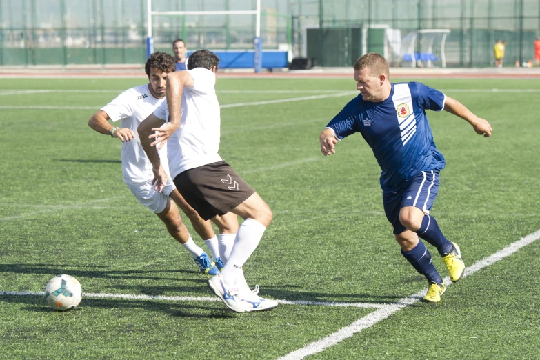 three men playing a game of soccer on a field