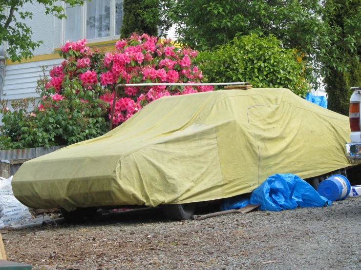 a covered car on the ground with many bags around it