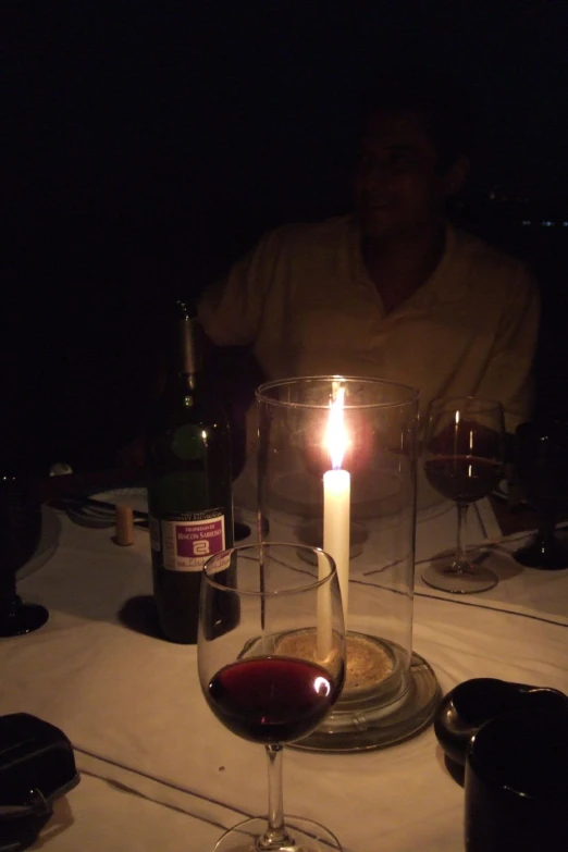 there is a candle lit by a wine glass and a bottle on the table