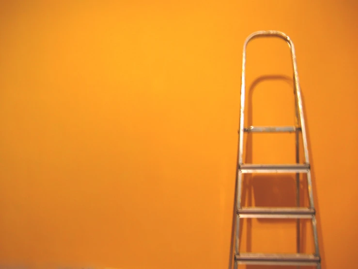 a ladder standing next to an orange wall