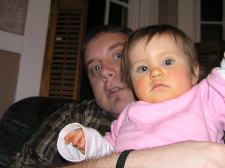 a man holding up a baby who has a cellphone in his hand