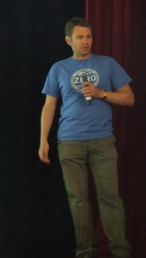 a man stands on a stage while holding a glass in his hand