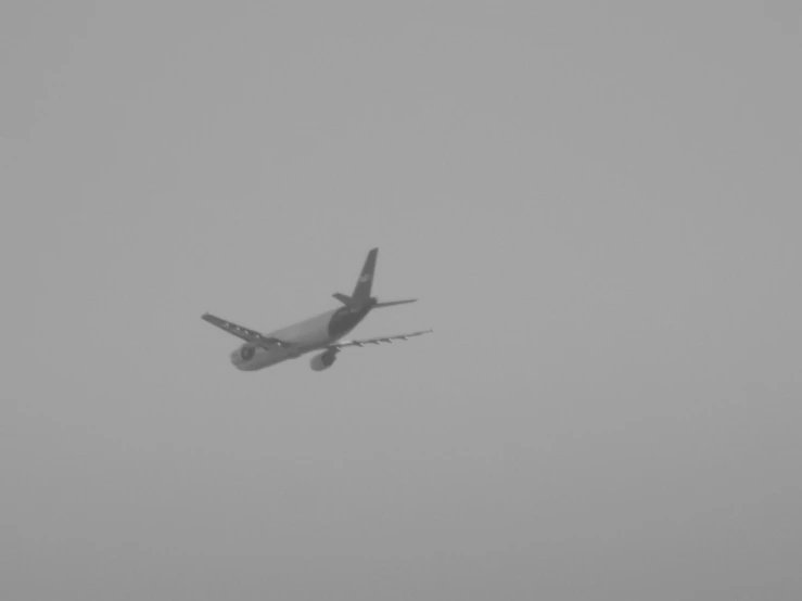 a plane flying in a foggy sky with no clouds