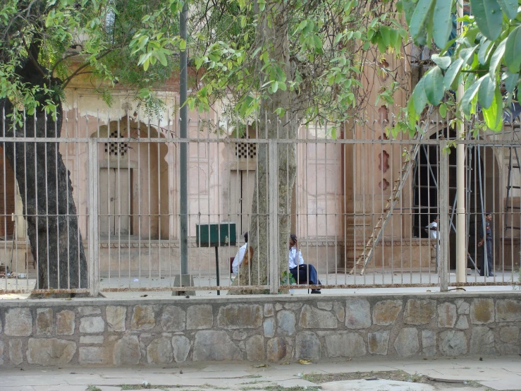 two people are sitting in front of a gated building