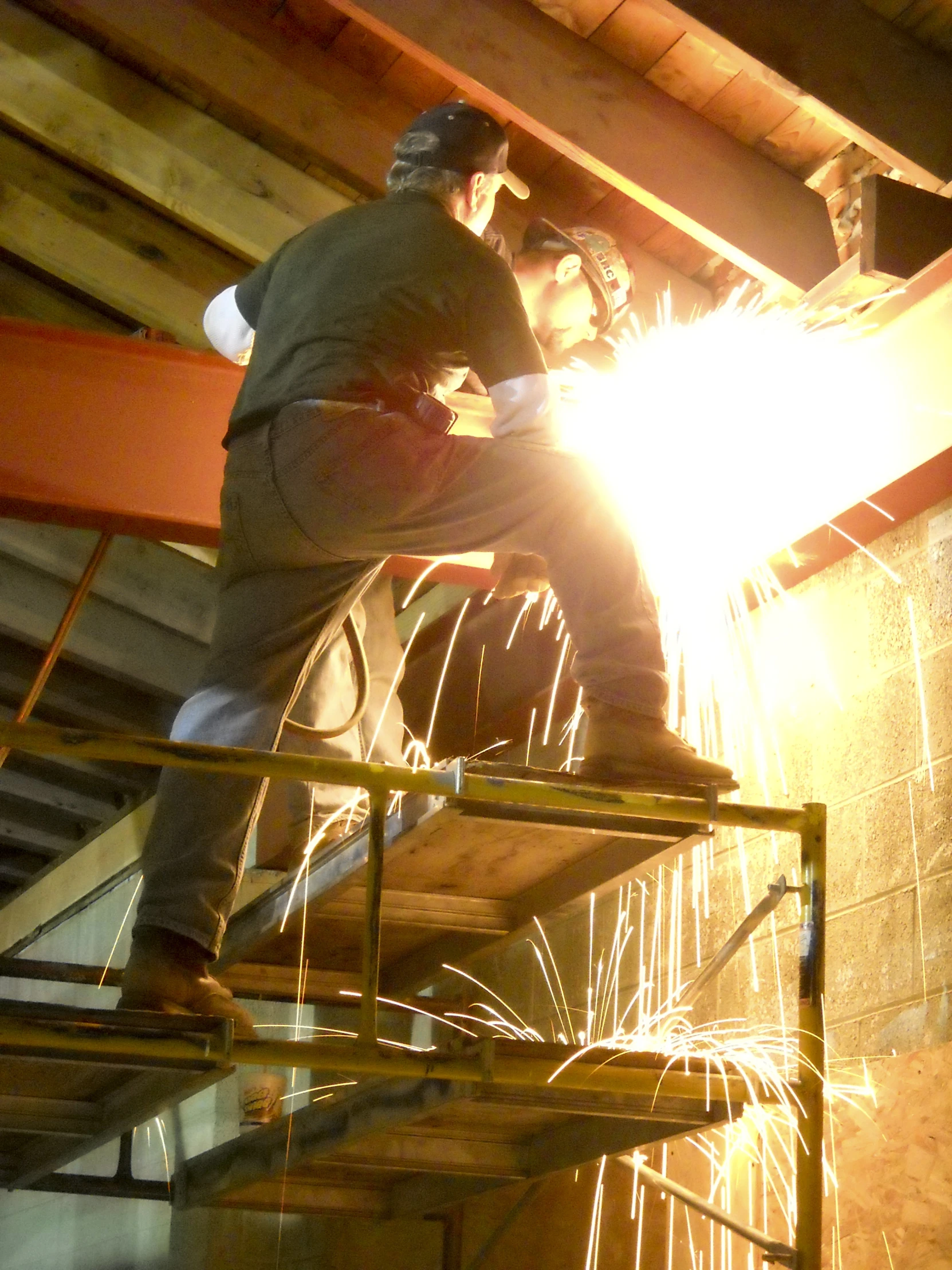 welders work on an overhead piece of metal