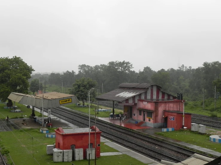 an old red train station sitting on top of a lush green hillside