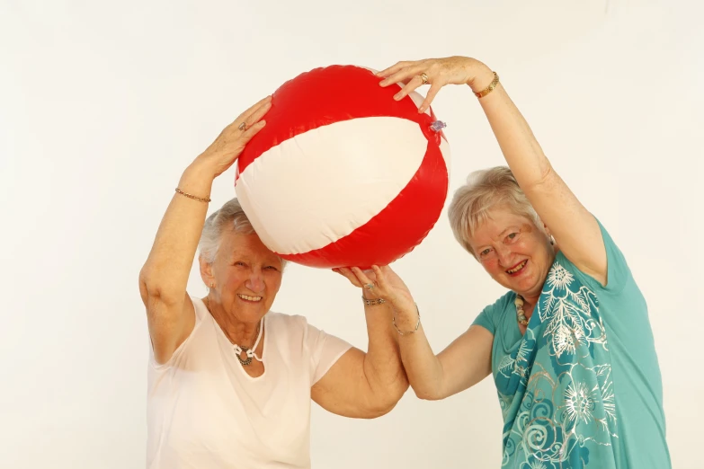 two women with white shirts and one holding a large red and white life - ball