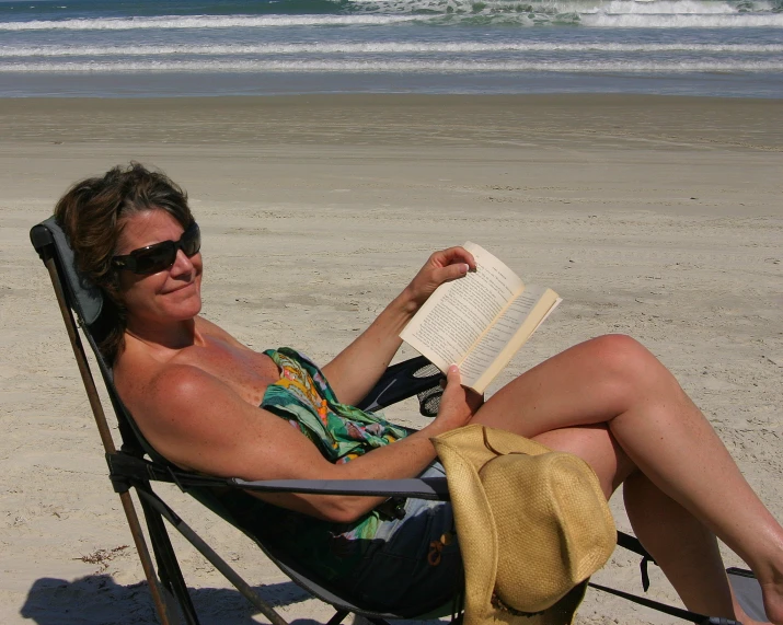 the woman is reading a book on the beach