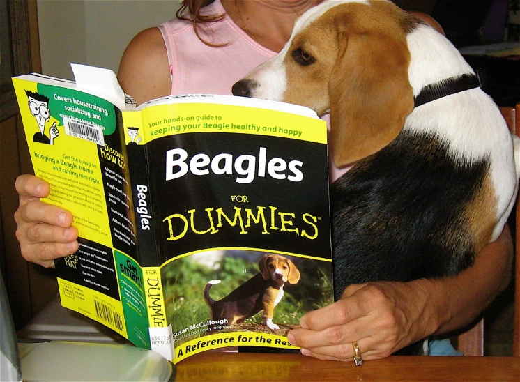 a woman reading a book with her dog looking at the front cover