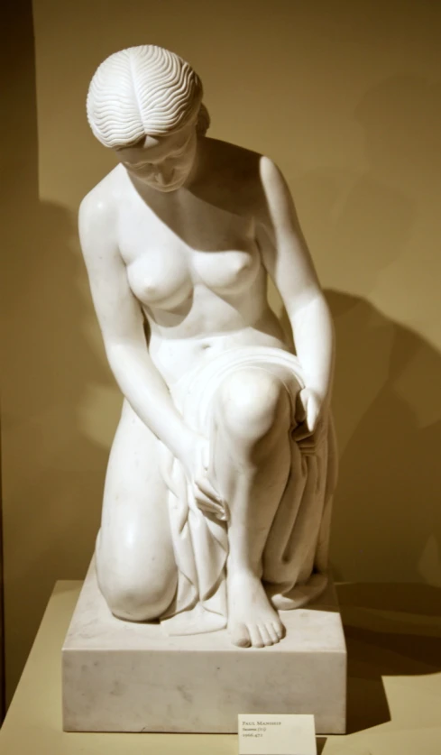 a white sculpture of a female  kneeling