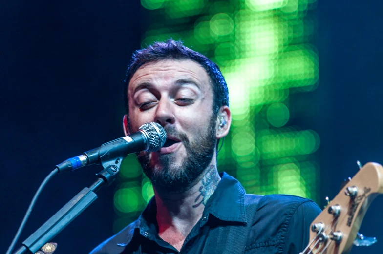 a male in a black shirt is playing guitar